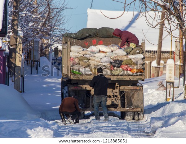 Workers collect\
garbage in a truck in\
winter