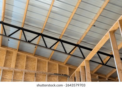 Workers are constructing building interior showing wooden framing metal roofing, highlighting structural features.