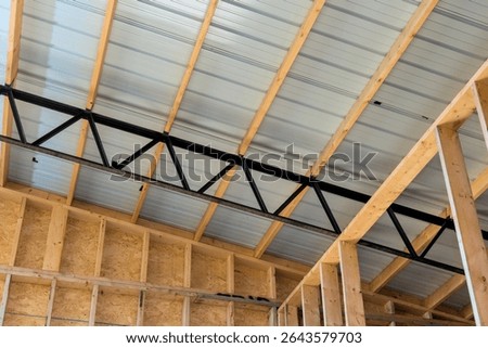 Workers are constructing building interior showing wooden framing metal roofing, highlighting structural features.