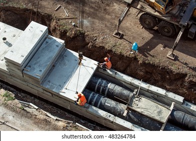 Workers constructing a trench for main heating pipes with a concrete elements and a cement