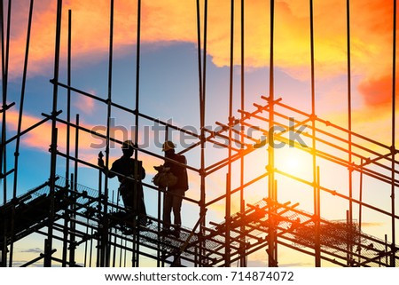 workers and construction site at sunset