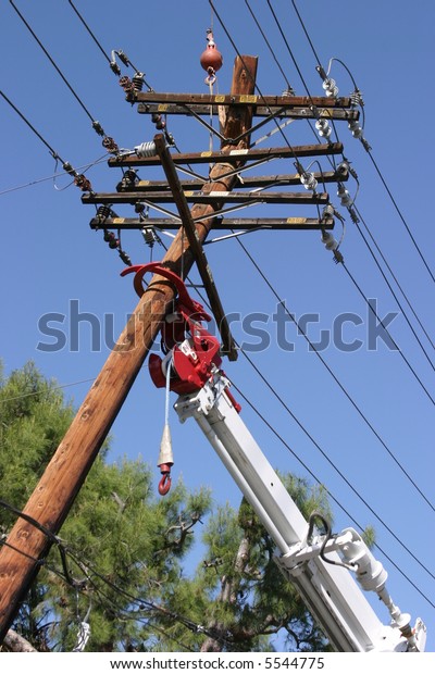 Workers with a\
crane with claws prepare to remove and replace a 95 foot utility\
pole broken by a car\
accident