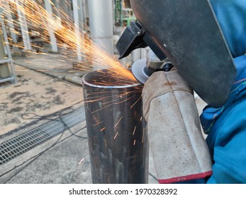 Workers Cutting Metal Pipe With Electric Grinder. Welder Is Wear Personal Protective Equipment(PPE) While Working. Leather Gloves And Face Shield.