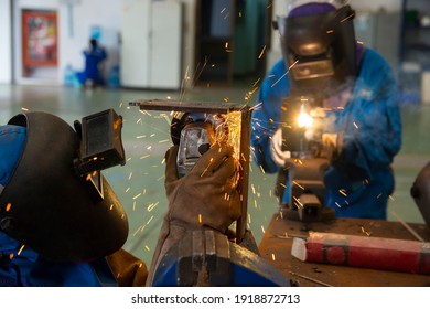 Workers Cutting Metal Sheets With Electric Grinder In The Workshop. Welder Is Wear Personal Protective Equipment(PPE) While Working. Leather Gloves And Face Shield.