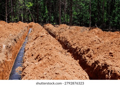 Workers are digging trenches in ground to install drainage pipes at construction area location