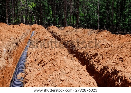 Workers are digging trenches in ground to install drainage pipes at construction area location
