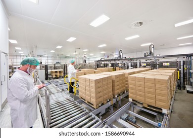 Workers with digital tablets at food packaging production line