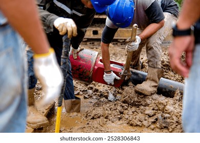 Workers disassembling an HDD reamer using special tools on a muddy construction site, showcasing the complexity of trenchless underground drilling operations
