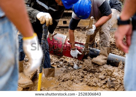Workers disassembling an HDD reamer using special tools on a muddy construction site, showcasing the complexity of trenchless underground drilling operations
