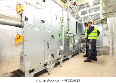 Workers In Electrical Switchgear Room Of CNC Plant