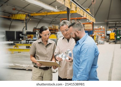 Workers examining metal parts in manufacturing plant - Powered by Shutterstock