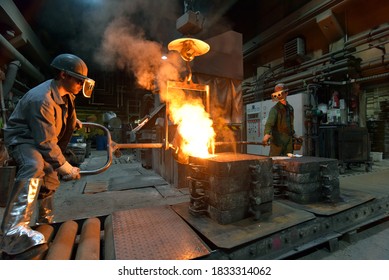 Workers In A Foundry Casting A Metal Workpiece - Safety At Work And Teamwork 