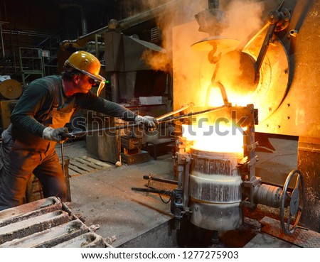 workers in a foundry casting a metal workpiece - safety at work and teamwork 