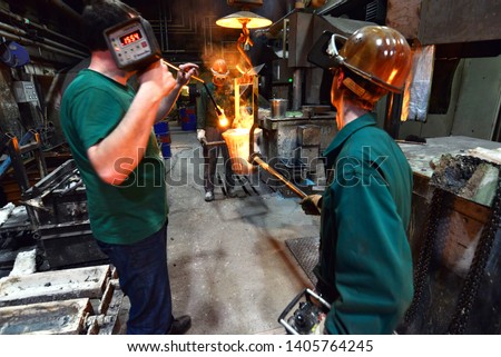 workers in a foundry casting a metal workpiece - safety at work and teamwork 