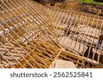 Workers are framing roof using wooden materials at busy construction site in work area.