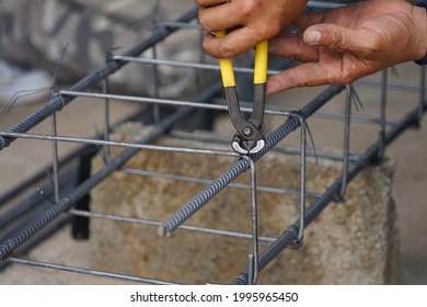 the worker's hand tying reinforcing steel bars, tightening wire on rebar using a pincers for formwork construction, selective focus