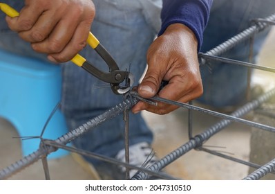 the worker's hand tying reinforcing steel bars, tightening wire on rebar using a pincers for formwork construction. selective focus                                              