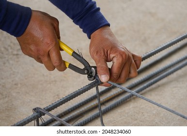 the worker's hand tying reinforcing steel bars, tightening wire on rebar using a pincers for formwork construction.                                                                        