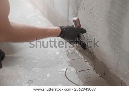 A worker's hand using a drywall spatula applies a  liquid membrane before inserting the corner reinforcement tape. Foolproof waterproofing for a tile bathroom. 
