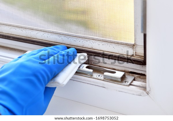 Worker\'s hand wipes dust and dirt on a plastic\
window, cleaning a mosquito net. A maid or housewife takes care of\
the house. General, regular cleaning. The concept of a commercial\
cleaning company