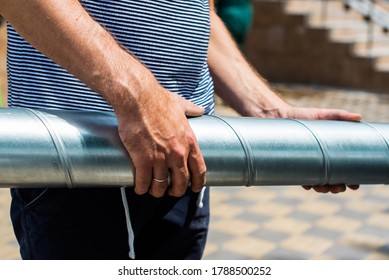 worker's hands are holding a metal pipe. repair of ventilation or plumbing. man do it yourself, fix your house. outside, sunlight, summer - Shutterstock ID 1788500252