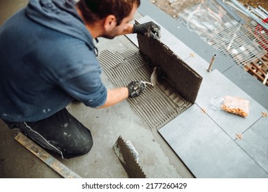 workers hands installing ceramic tiles on the balcony floor. a handyman using a tile spacer to adjust the tile level. Repair work, construction details