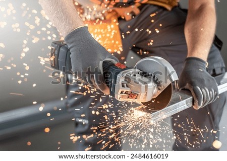 Worker's hands shortens a ceiling C profile with angle grinder. Assembling the support structure from ceiling C profiles for plasterboard.  