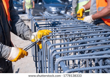workers hands using iron wire for securing iron bars with wire rod for reinforcement iron reinforcement in the construction site