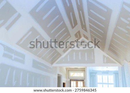 Workers have installed drywall in interior of house, with lines seams on walls ceiling.
