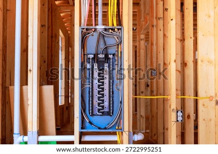Workers have installed an electrical panel in beams framework of house being built at residential neighborhood.