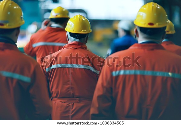 workers  helmets at the\
factory, view from the back, group of workers,  change of workers\
in the factory, people go in helmets and uniforms for an industrial\
enterprise