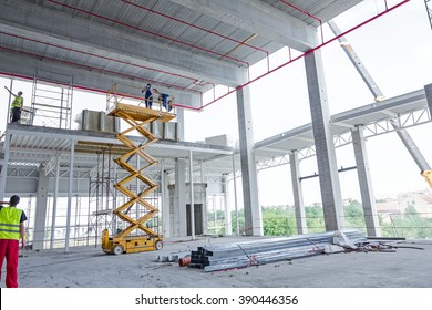 Workers Are High Up In Cherry Picker On Building Site.