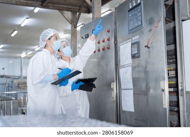 Workers inspecting control panel in factory, Quality control inspectors monitoring industrial machine control panel in a factory, Technicians checking electronic equipment in a food processing plant