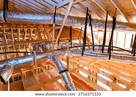 Workers install ductwork in ceiling of building that is under construction is wooden beams