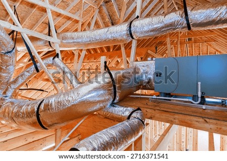 Workers install ductwork ventilation unit inside wooden frame structure