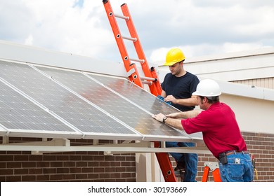 Workers Install Energy Efficient Solar Panels On The Roof Of A Building.