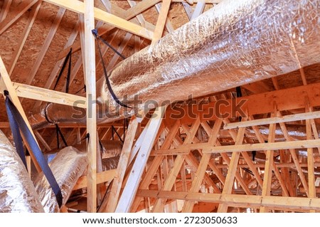 Workers install metal ductwork in ceiling of building that is being constructed