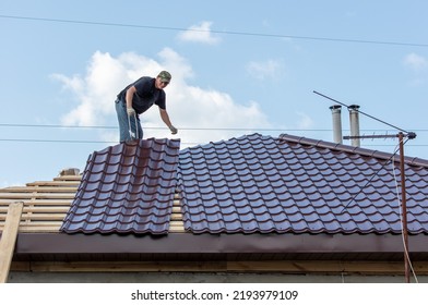 Workers install metal roofing on the wooden roof of a house. Technology - Shutterstock ID 2193979109