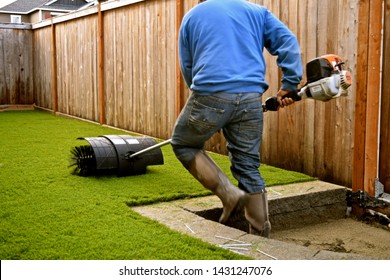 Workers installing artificial turf in a residential yard.