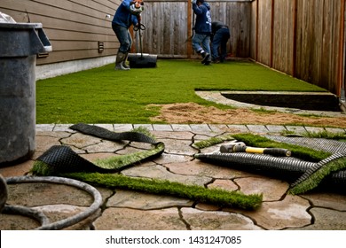 Workers Installing Artificial Turf In A Residential Yard.