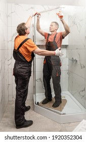 Workers Are Installing Glass Door Of The Shower Enclosure.