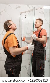 Workers Are Installing Glass Door Of The Shower Enclosure.