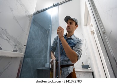 Workers Are Installing Glass Door Of The Shower Enclosure.