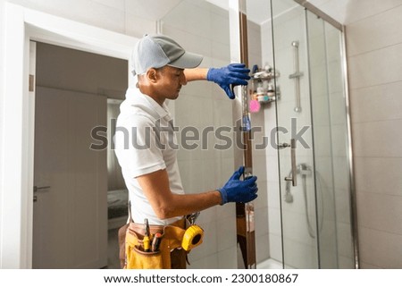 Workers are installing glass door of the shower enclosure