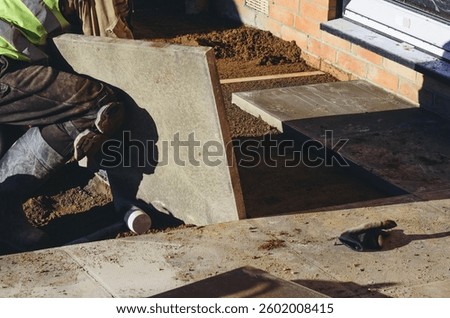 Workers installing large stone slabs to create walkway in front of residential building
