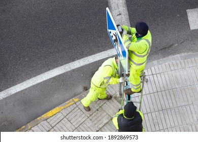 Workers Installing A New Road Sign On Street Sidewalk. Public Maintenance Concept