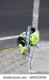 Workers installing a new road sign on street sidewalk. Public maintenance concept