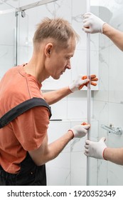 Workers Are Installing A Silicone Gasket Seal On The Glass Door Of The Shower Enclosure.