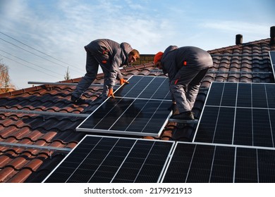 workers installing solar panels on the roof - Shutterstock ID 2179921913