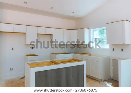Workers are installing white kitchen cabinets preparing space for finishing touches in new home.
